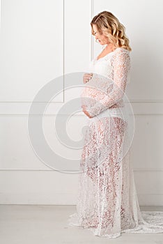 Beautiful Pregant blonde woman holding his belly in light study
