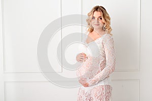 Beautiful Pregant blonde woman holding his belly in light study