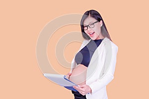 A beautiful pregnant Asian woman holding a paper binder, relaxing and enjoying her work