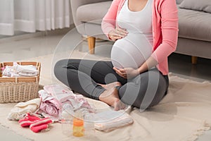 Beautiful pregnant asian woman packing and preparing baby clothes in basket for expectant new born baby