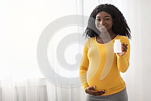 Beautiful pregnant black woman showing her supplements