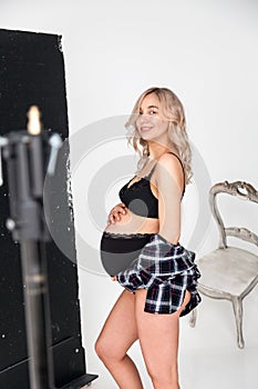 Beautiful pregnant blonde woman in underwear at a photo session in the studio with equipment for high-quality and beautiful