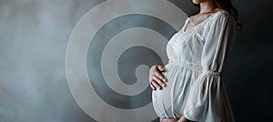 Pregnant caucasian woman in white dress holding hands on belly photo