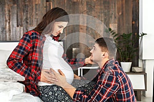 Beautiful pregnant couple in the bedroom. Preparing for childbirth, happy parents, waiting for the first child. Support