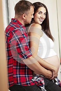 Beautiful pregnant couple smiling and hugging. Love and tenderness in anticipation of a miracle.