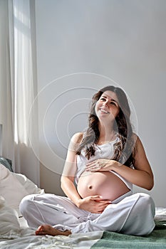 a beautiful pregnant girl holds her stomach with her hands and smiles