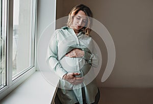 beautiful pregnant girl stands near the window