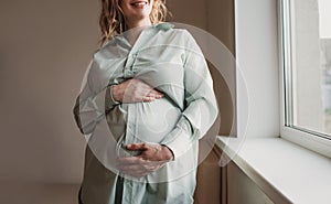 beautiful pregnant girl stands near the window