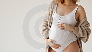 A beautiful pregnant girl in a white bodysuit and an oversized jacket, wavy hair. A pregnant beauty is