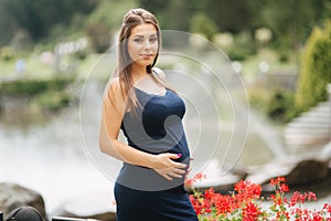 Beautiful pregnant lady in blue dress smile. Tenderness woman walk outside. Six months of pregnancy