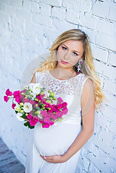 Beautiful pregnant lady with a bouquet of flowers waiting for the baby. Pregnancy.