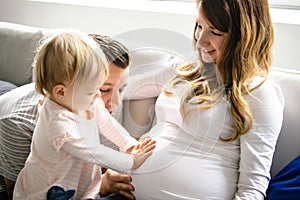 A Beautiful pregnant mother and father with her children girl at the living room