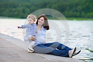 Beautiful pregnant mother and her baby daughter in river shore