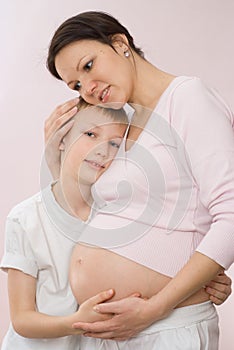 Beautiful pregnant mother tenderly embracing son