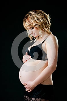 Beautiful pregnant mother with tenderness looks at tummy