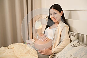 Beautiful pregnant woman applying moisturizing, stretch mark cream on belly, fertility infertility treatment, IVF, future