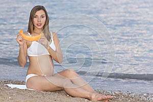 A beautiful pregnant woman on the beach touching her belly