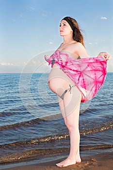 Beautiful pregnant woman in bikini on beach.