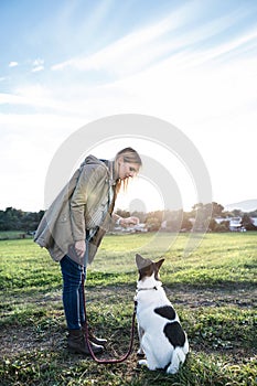 Beautiful pregnant woman with dog in green sunny nature