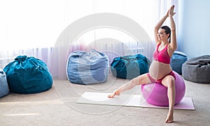 Beautiful pregnant woman doing exercises on a fitness ball. Expectant mother in the last trimester doing yoga.
