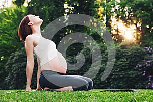 Beautiful pregnant woman doing prenatal yoga on nature outdoors.