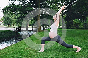 Beautiful pregnant woman doing prenatal yoga on nature outdoors.