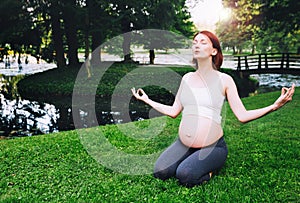 Beautiful pregnant woman doing prenatal yoga on nature outdoors.