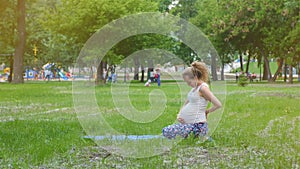 Beautiful pregnant woman doing prenatal yoga on nature outdoors. Sport, fitness, healthy lifestyle while pregnancy