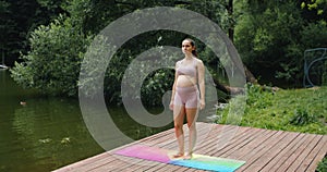 Beautiful pregnant woman doing prenatal yoga on nature outdoors. Sport, fitness, healthy lifestyle while pregnancy