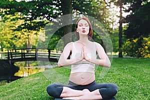 Beautiful pregnant woman doing prenatal yoga on nature outdoors.