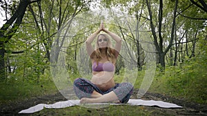 Beautiful pregnant woman doing prenatal yoga on nature outdoors. Sport, fitness, healthy lifestyle while pregnant