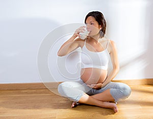 Beautiful pregnant woman drinking milk at home