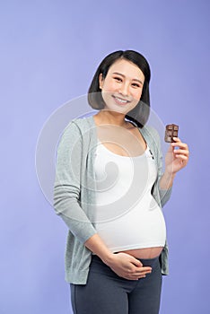 Beautiful pregnant woman eating chocolate at home