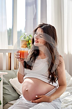 a beautiful pregnant woman eats right and drinks fresh natural juice