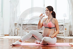 Beautiful pregnant woman excercising in a bright room