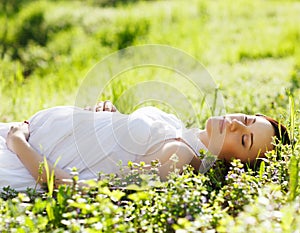 Beautiful pregnant woman on grass in the spring park