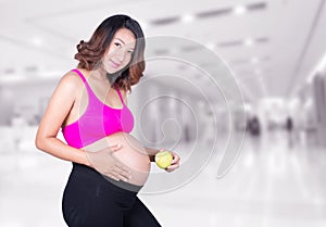 Beautiful pregnant woman with green apple in hospital
