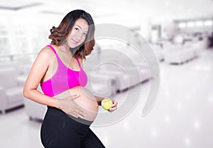 Beautiful pregnant woman with green apple in hospital