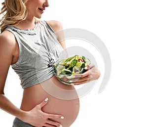 Beautiful pregnant woman hold organic salad and fork with tomato. Pregnancy motherhood expectation healthy eating