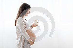 Beautiful pregnant woman holding glass of milk