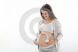 Beautiful pregnant woman holding headphones on big tummy