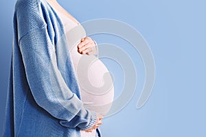 Beautiful pregnant woman hugging her belly in white background. Expectant mother waiting for baby birth during pregnancy. Concept