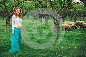 Beautiful pregnant woman laughing and walking on a green meadow