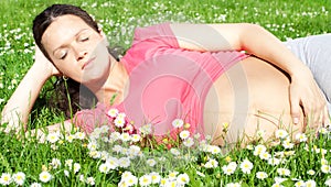 Beautiful pregnant woman laying on grass