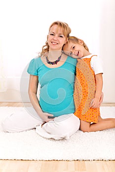 Beautiful pregnant woman and little girl hugging