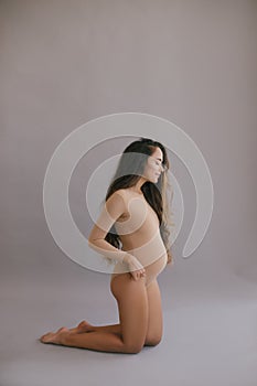 Beautiful pregnant woman with long hair on grey background