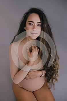 Beautiful pregnant woman with long hair on grey background