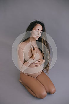 Beautiful pregnant woman with long hair on grey background