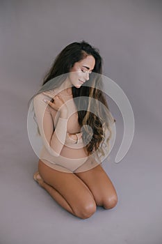 Beautiful pregnant woman with long hair on grey background