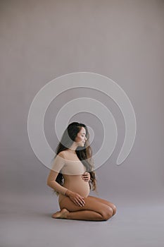 Beautiful pregnant woman with long hair on grey background